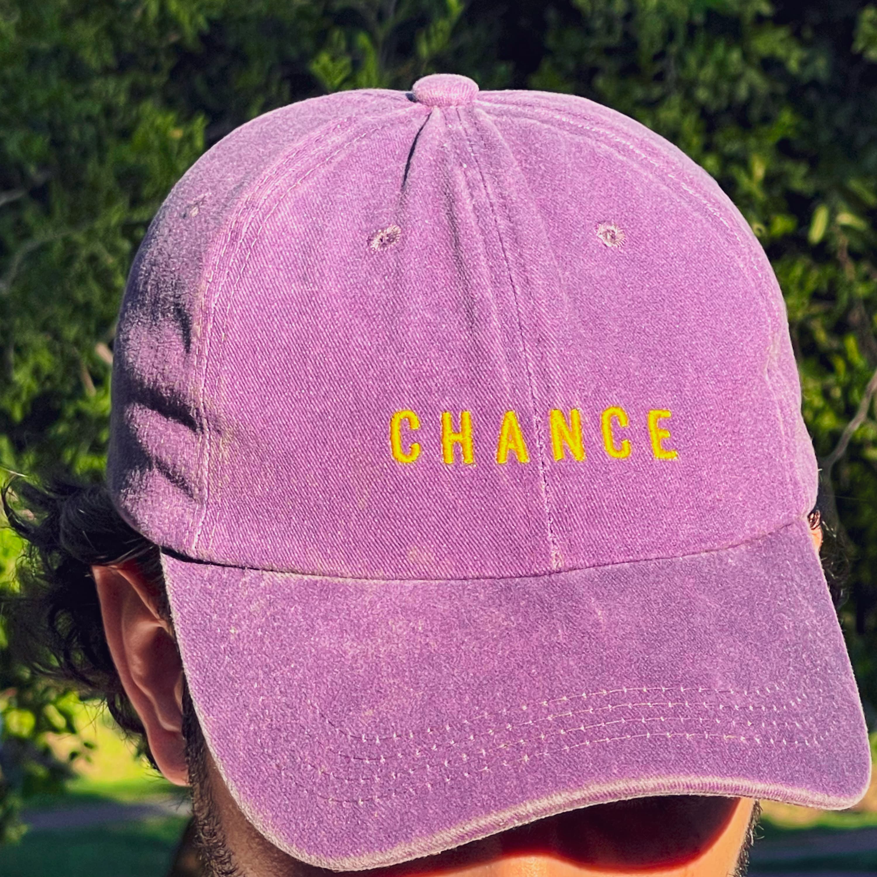 gorra violeta clasica con letras amarillas que dicen CHANCE